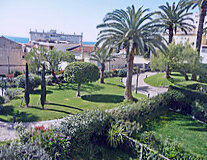 a park with palm trees and a building in the background